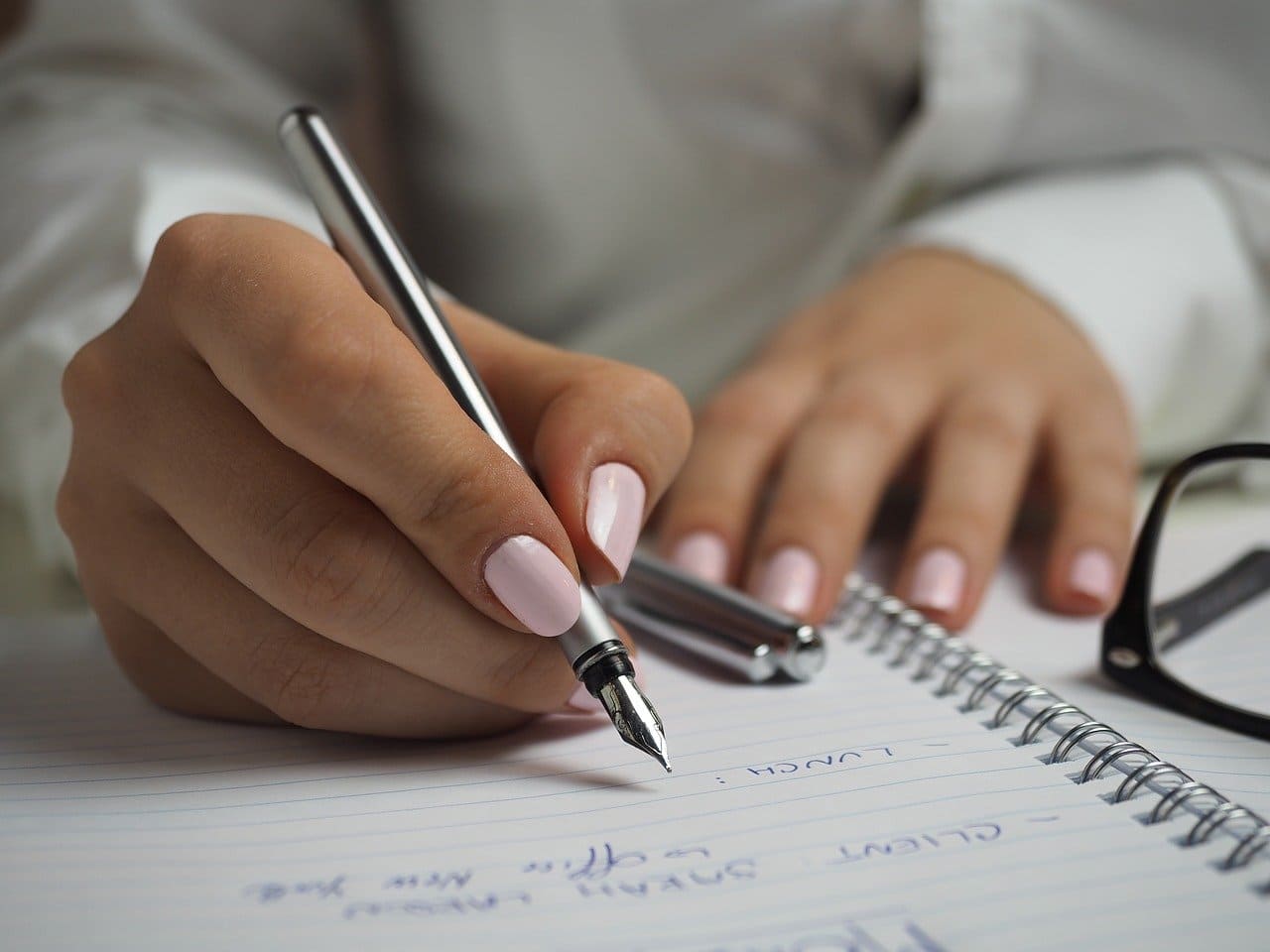 女性が紙にペンで字を書いている