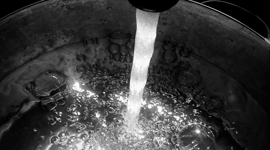 ステンレスの鍋に消毒液と、蛇口から水を入れている。