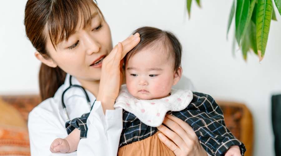 女医が赤ちゃんの頭を撫でている。